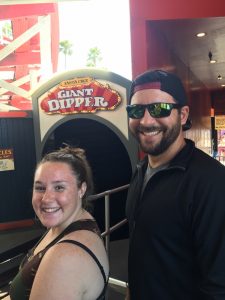 woman and man smile in front of giant dipper sign